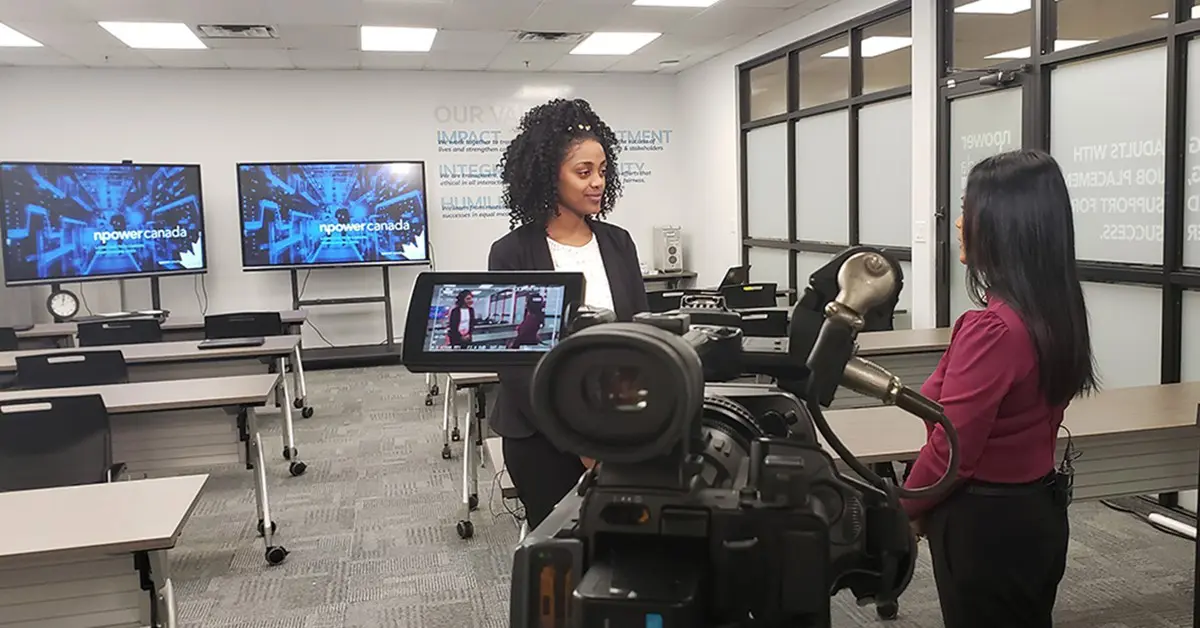 Interviewer speaking to an NPower Canada representative in a classroom with a camera in front