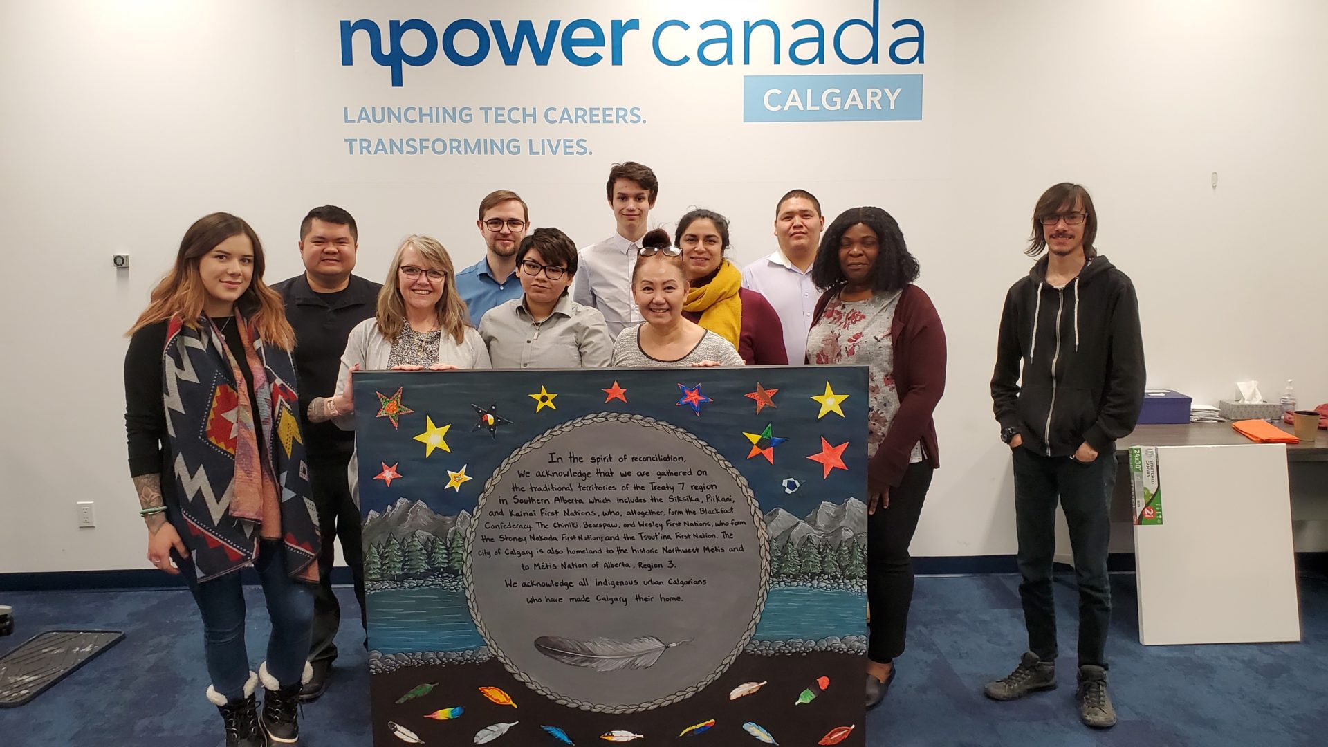 Groupe de personnes tenant une œuvre d'art sur le thème de Autochtones dans les bureaux de NPower Canada à Calgary.